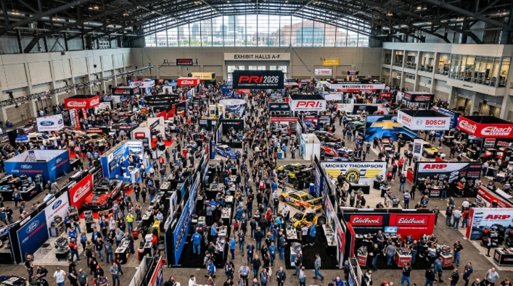 Aerial view of the packed PRI Show 2026 exhibition floor at the Indiana Convention Center in Indianapolis, with motorsports exhibitors and thousands of industry professionals filling every aisle