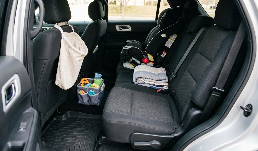 Parent vacuuming car seats with a handheld vacuum